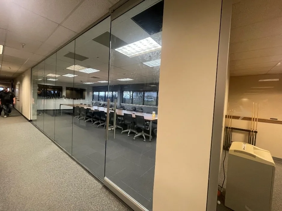 Conference room with a floor-to-ceiling glass wall, viewed from the corridor after the build-out