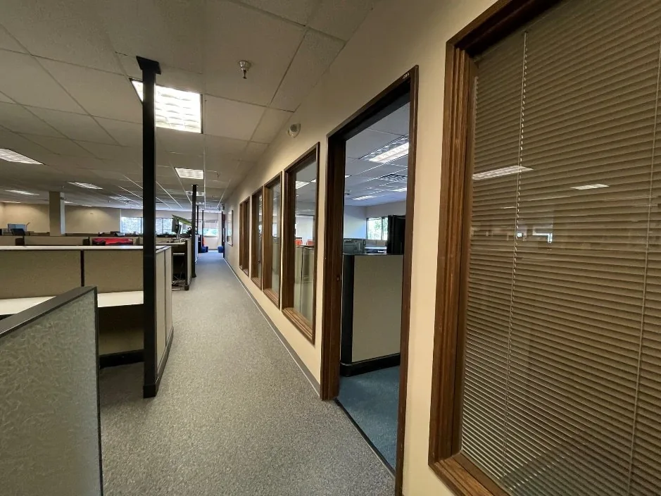 Office corridor with wood-framed windows and blinds before the conference room build-out